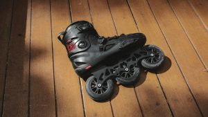Single black rollerblade on wood plank floor